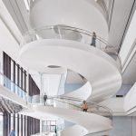 3-story curved white staircase with people walking on it