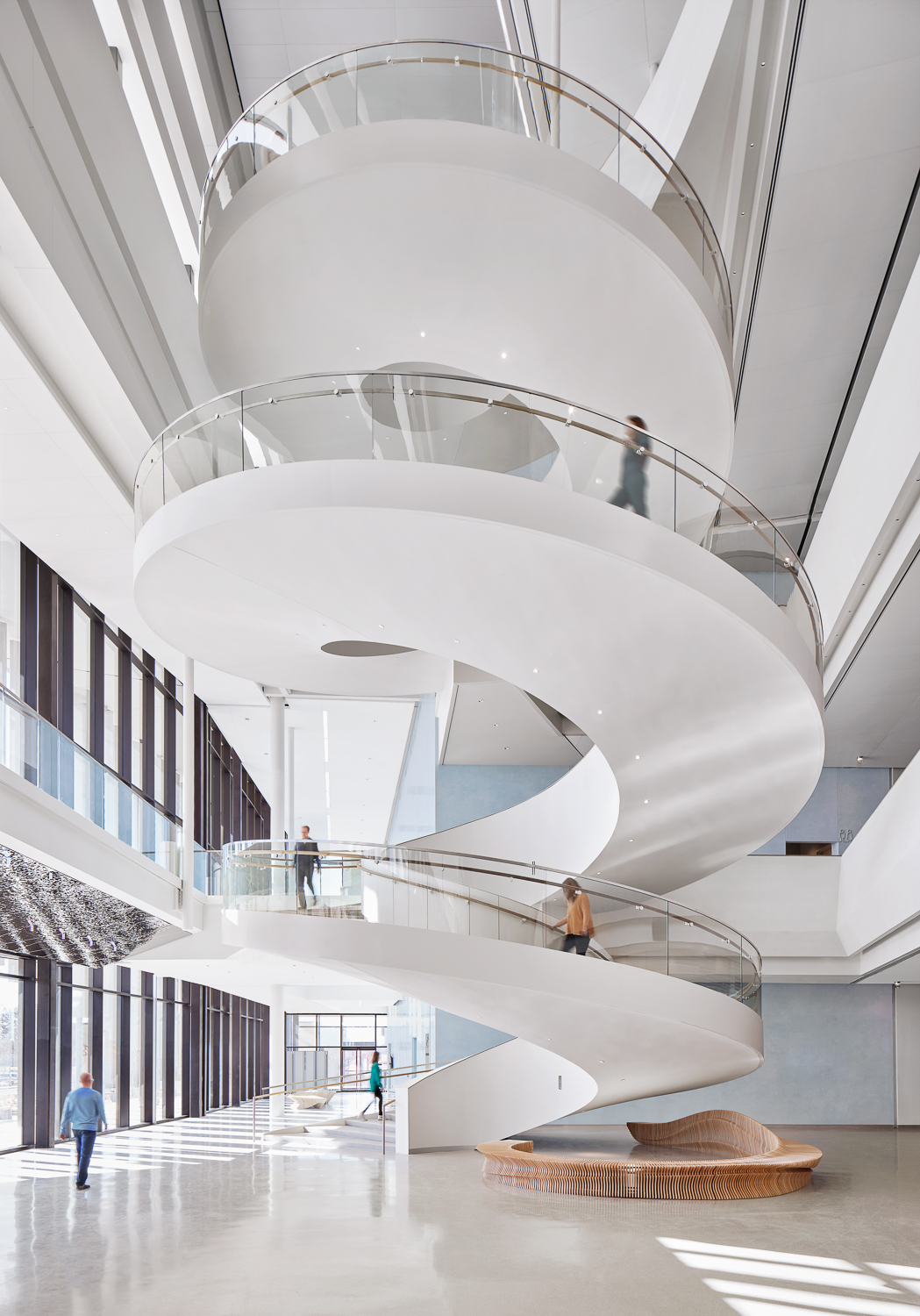 3-story curved white staircase with people walking on it