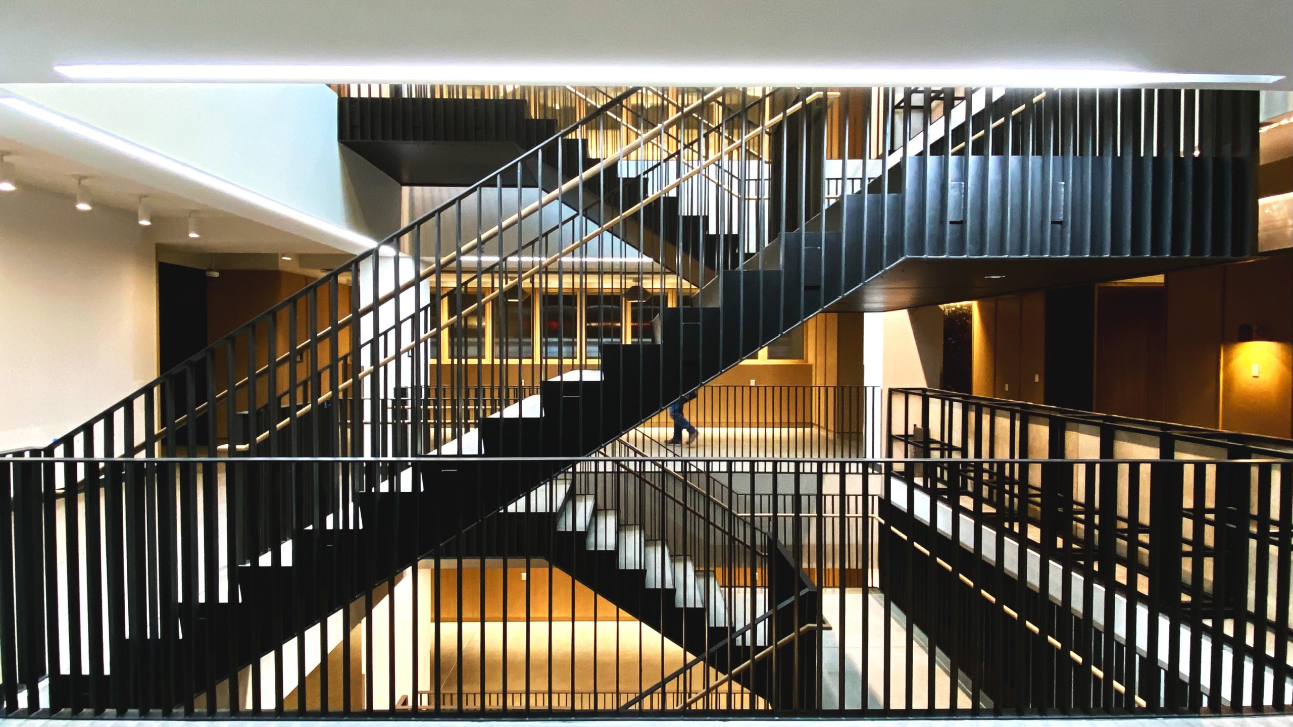 Black steel staircase with wood handrails inside building atrium