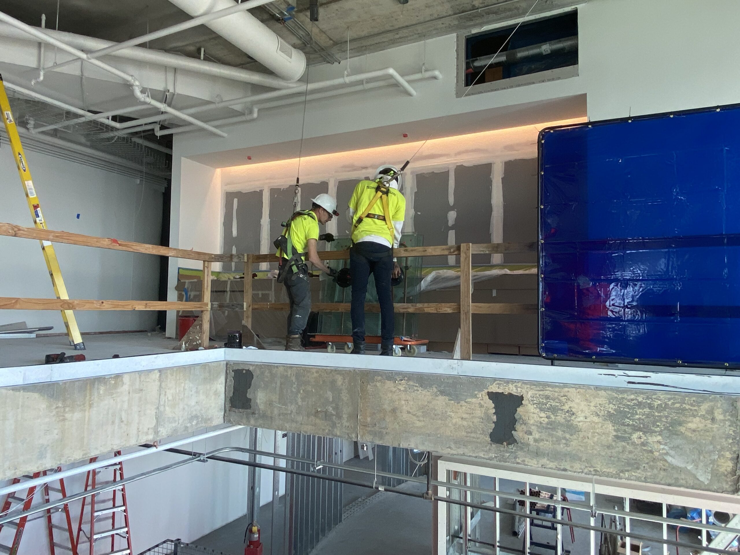 workers properly using PFAS (personal fall arrest system) to install perimeter glass panels