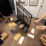 Four people surround a round table with various materials used to finish a stair.