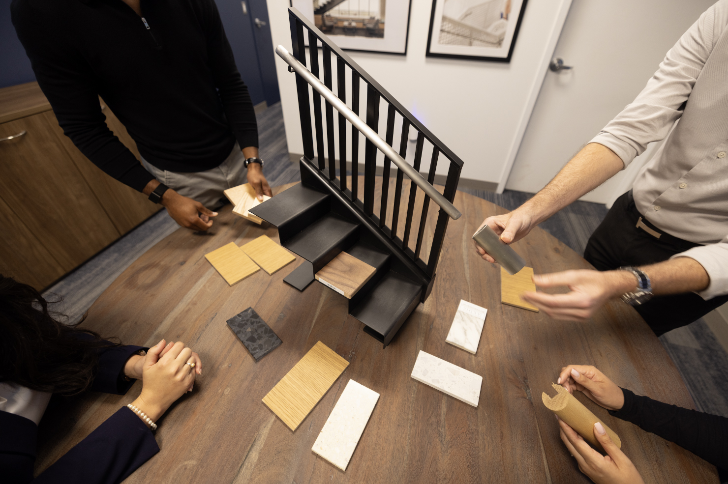 Four people surround a round table with various materials used to finish a stair.