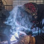 welder-wearing-helmet-and-gloves-with-smoke