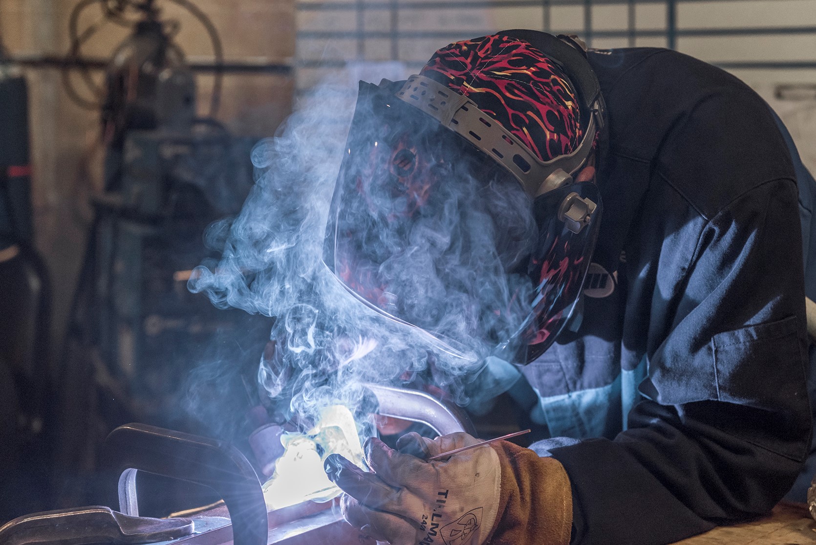 welder-wearing-helmet-and-gloves-with-smoke
