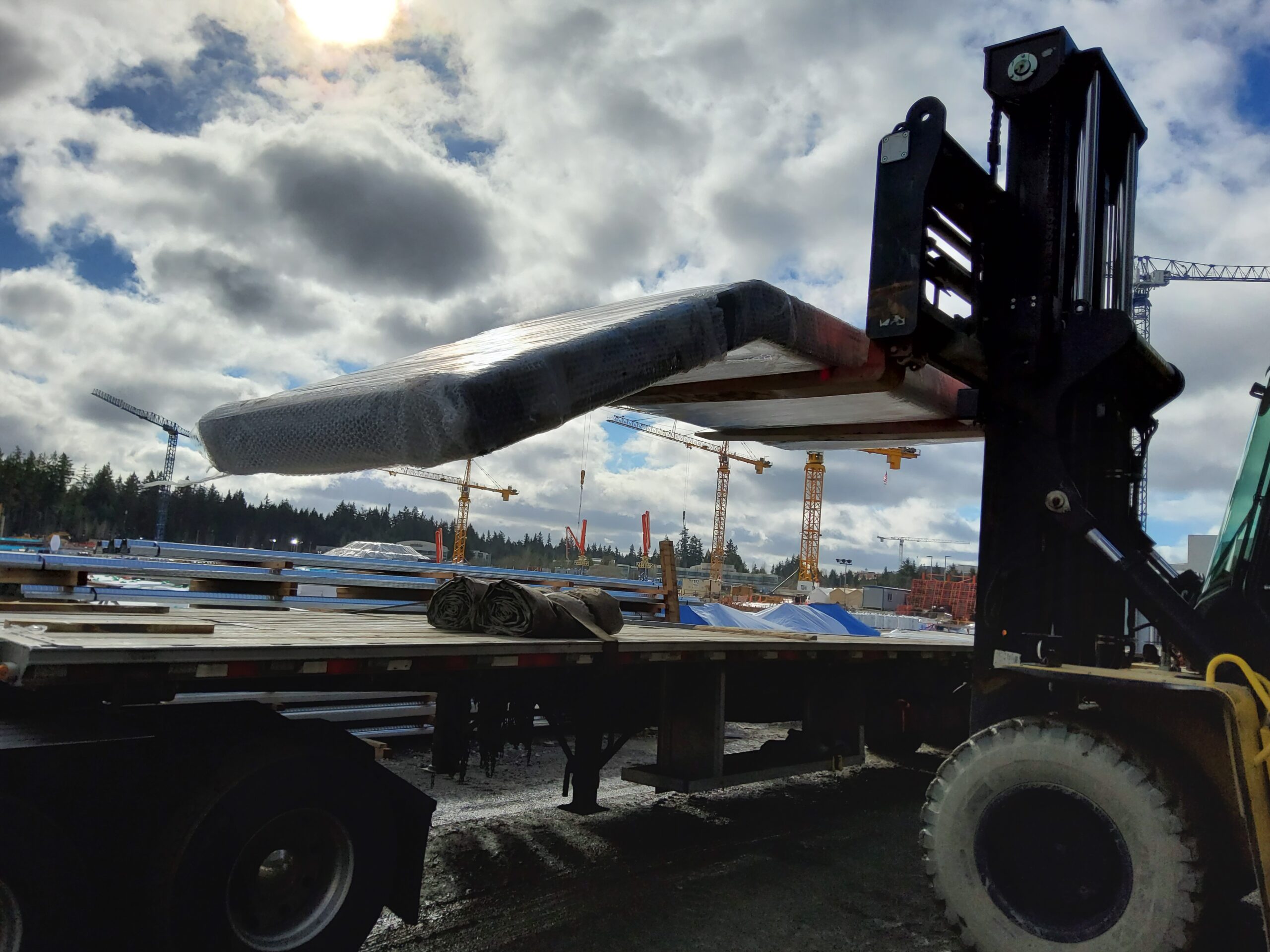 Prefabricated modular feature stair covered in bubble wrap being lifted off a delivery truck on a construction site