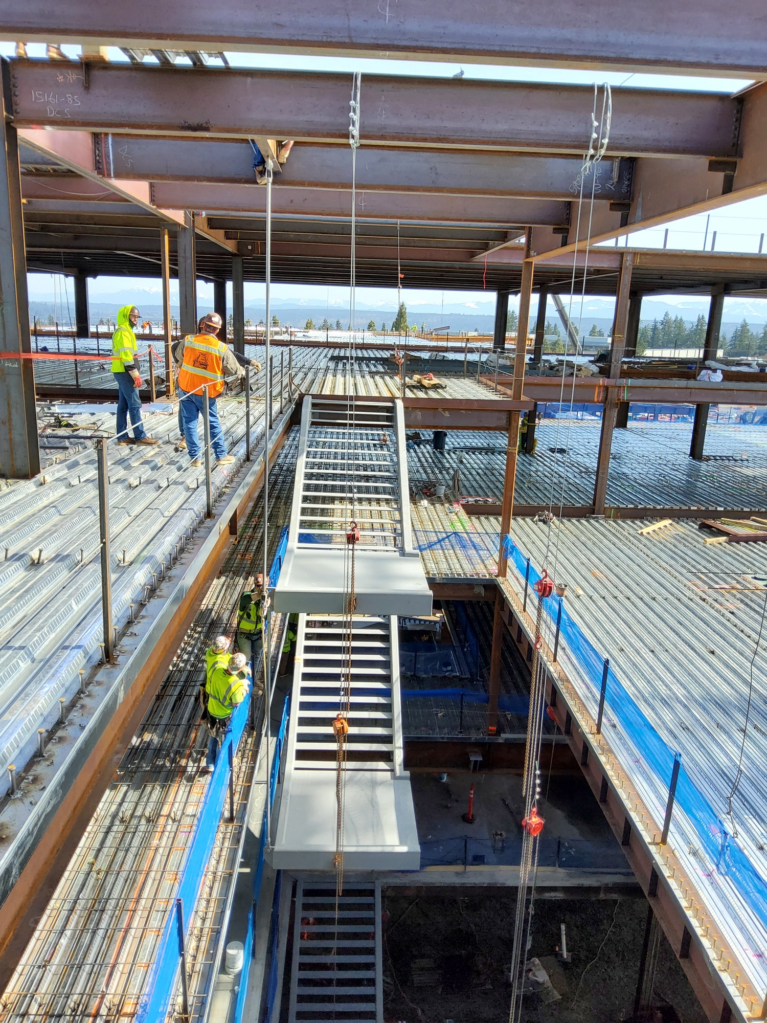Two prefabricated modular feature stairs being craned into building under construction